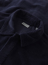 Close-up of a dark navy corduroy button-up shirt collar, showing the ribbed texture and a small white neck label.