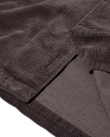 Close-up of a dark grey corduroy garment, showing the ribbed texture and an embroidered 'Gellibrand' logo on a white background.