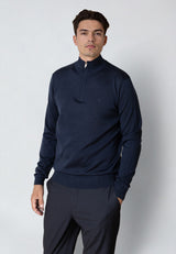 Man wearing a navy blue quarter-zip sweater and pants on a light gray background