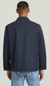 Person wearing a navy shirt and light blue jeans on a plain background