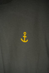 Close-up of a dark charcoal gray t-shirt featuring a small yellow anchor graphic printed on the chest.