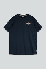 A navy blue short-sleeve crewneck t-shirt with a small pink and white graphic on the left chest, displayed flat against a light gray background.