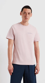 Man wearing a light pink t-shirt with a small logo on a white background