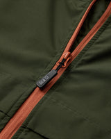 Close-up of a green jacket with a brown zipper and a visible brand logo.