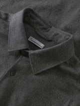 Close-up of a dark gray textured knit polo shirt collar with a visible white brand tag reading 'The North Face'.