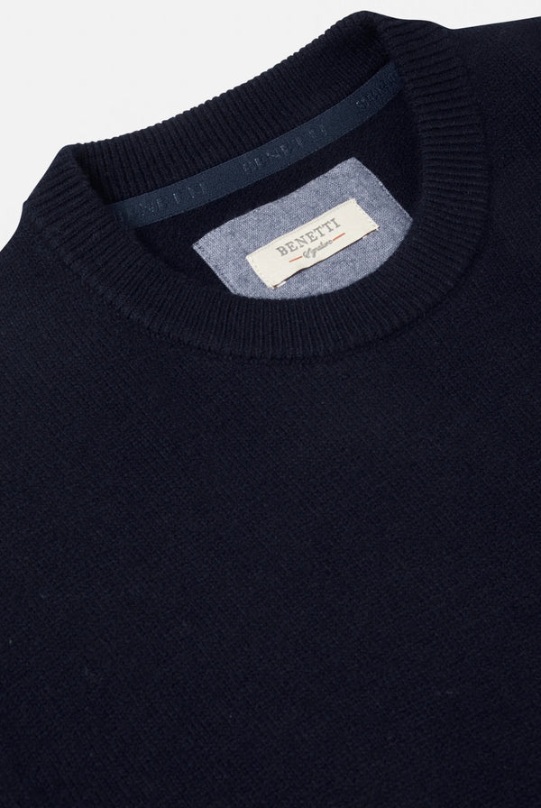 Navy sweater with a brand label on the collar against a light gray background