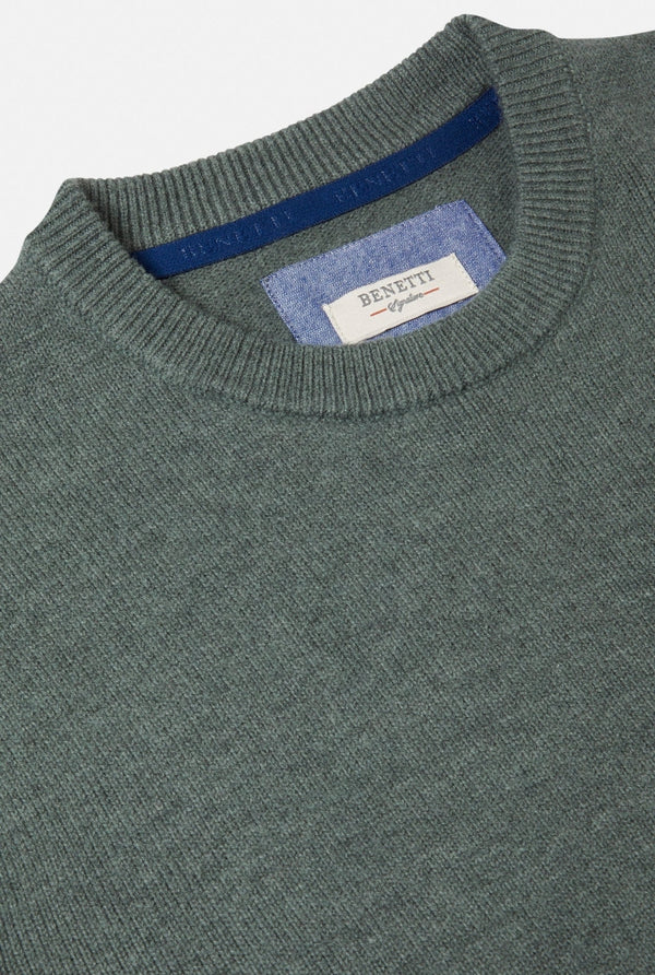Green sweater with a visible brand label on a light gray background