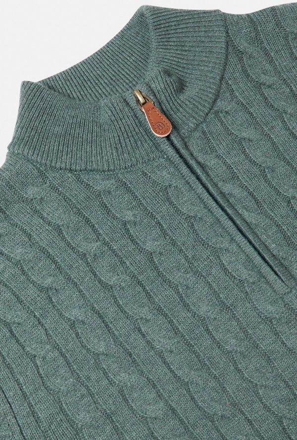 Teal cable knit sweater with a leather patch on a light gray background