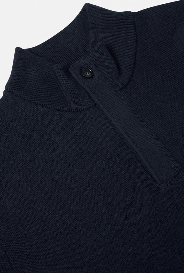Close-up of a dark blue garment with a button on a light gray background