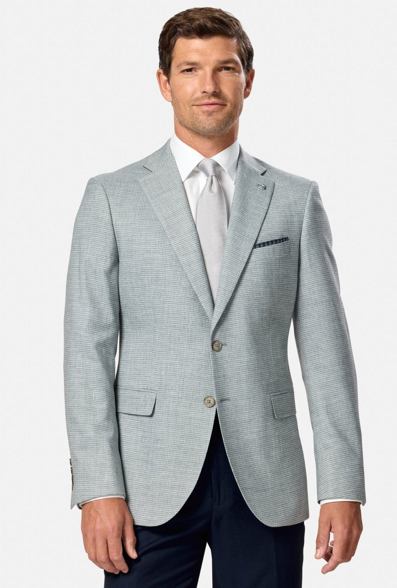 Man wearing a light green checkered blazer over a white shirt with a tie on a white background