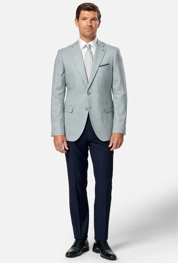 Man wearing a light green blazer, white shirt, and dark blue pants on a white background