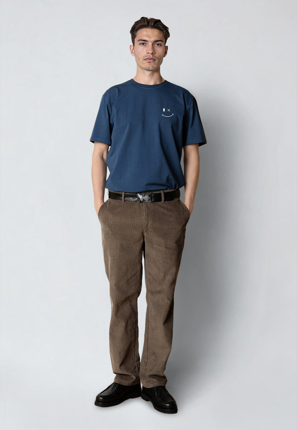 Man wearing a blue t-shirt and brown pants on a white background