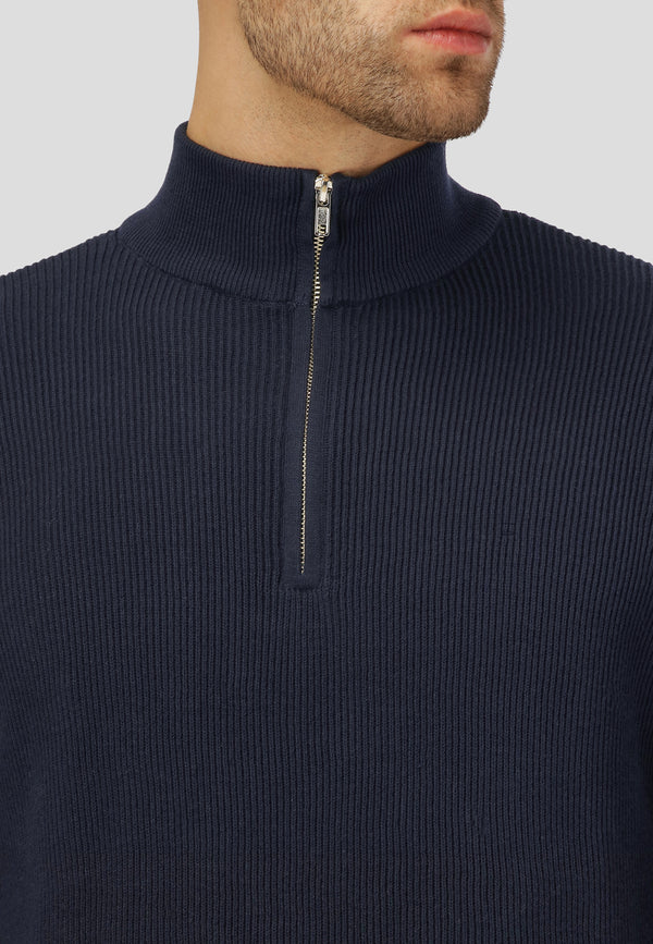 Navy blue ribbed sweater with a quarter zip on a neutral background