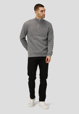 Man wearing a gray sweater and black pants on a light gray background