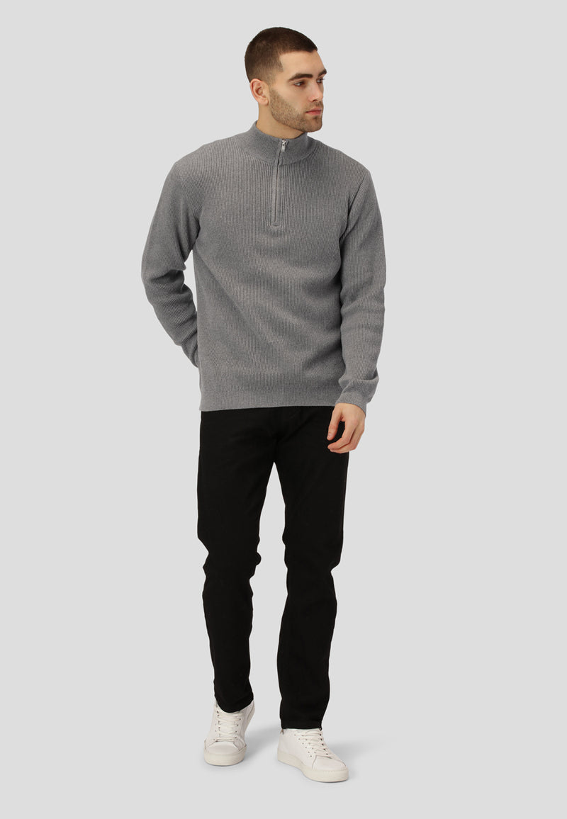Man wearing a gray sweater and black pants on a light gray background