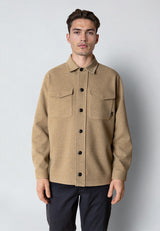 Man wearing a beige button-up shirt against a plain background