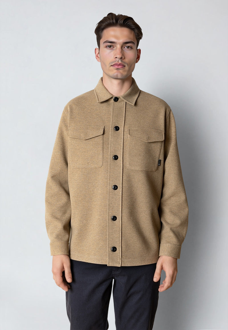 Man wearing a beige button-up shirt against a plain background