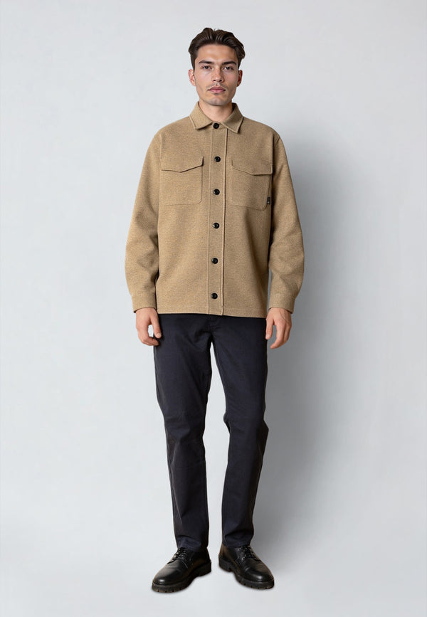 Man wearing a beige jacket and black pants on a white background