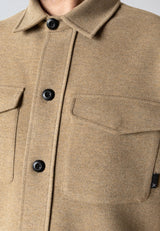 Close-up of a beige jacket with black buttons and a pocket.