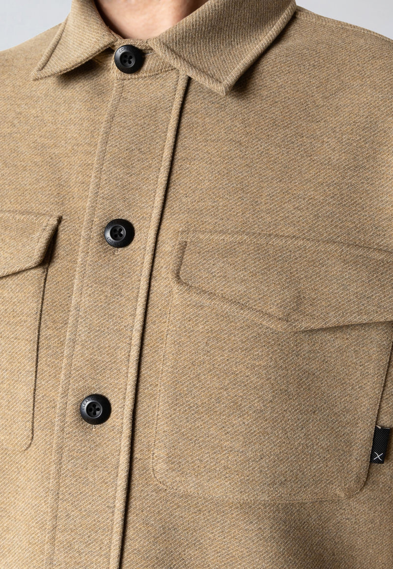Close-up of a beige jacket with black buttons and a pocket.