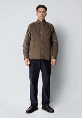 Man wearing a brown corduroy shirt and dark pants on a white background