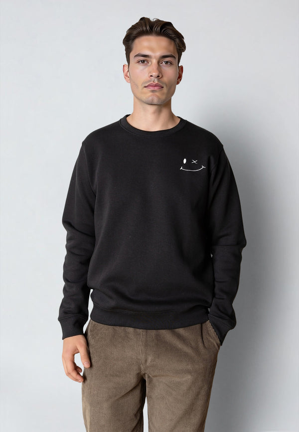 Man wearing a black sweatshirt with a small logo on a plain background