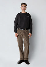 Man wearing a black sweatshirt and brown pants on a white background
