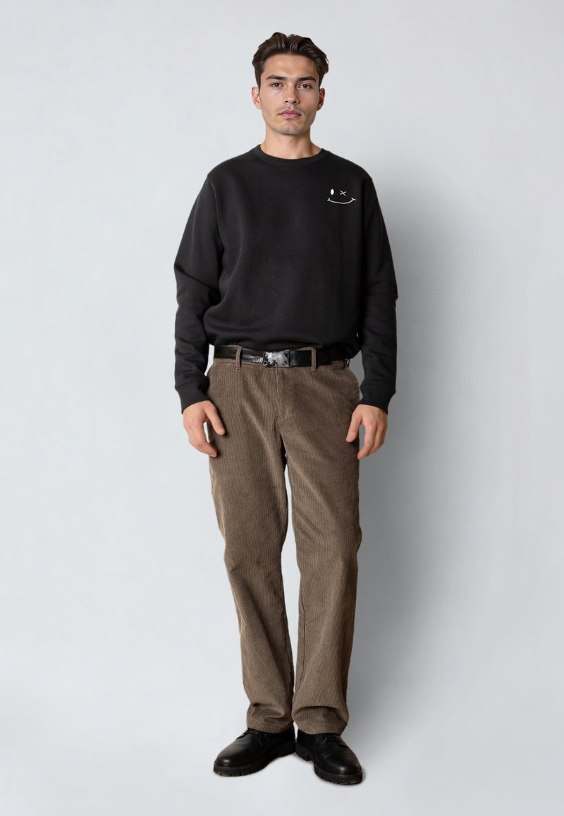 Man wearing a black sweatshirt and brown pants on a white background