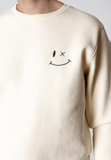 Beige sweatshirt with a smiley face design on a plain background