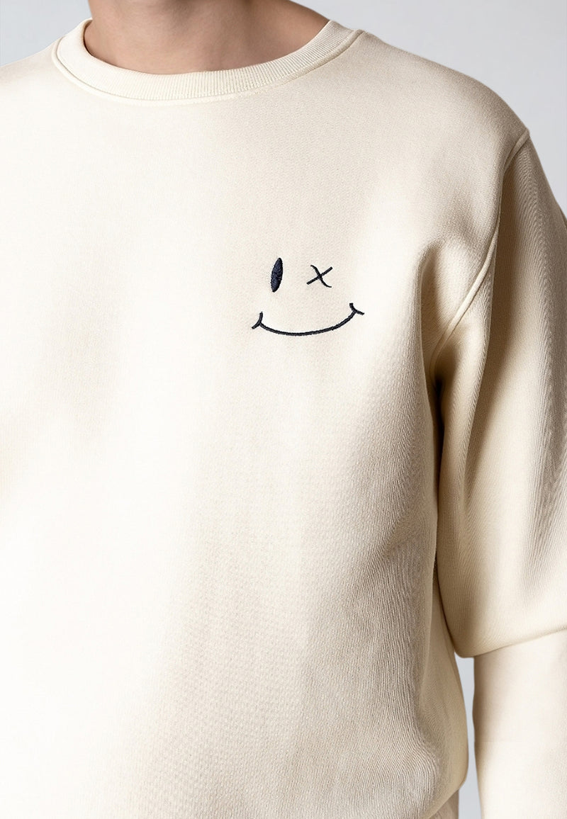 Beige sweatshirt with a smiley face design on a plain background