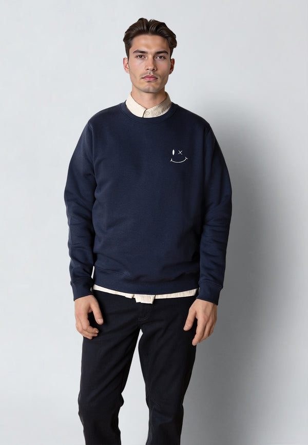 Man wearing a navy blue sweatshirt with a smiley face design on a plain background