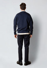 Man wearing a navy blue sweatshirt and black pants against a white background