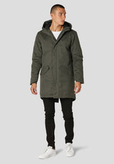 Man wearing a green parka coat on a light gray background