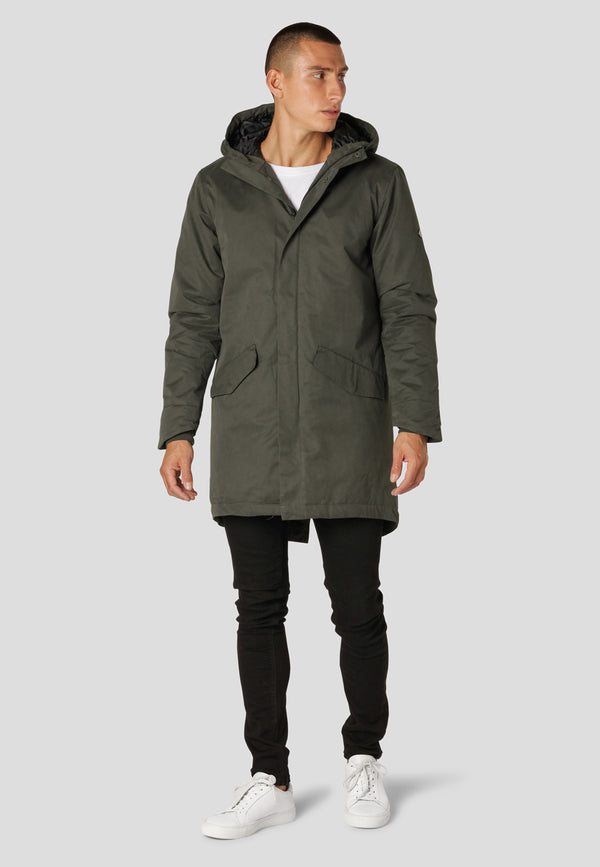 Man wearing a green parka coat on a light gray background