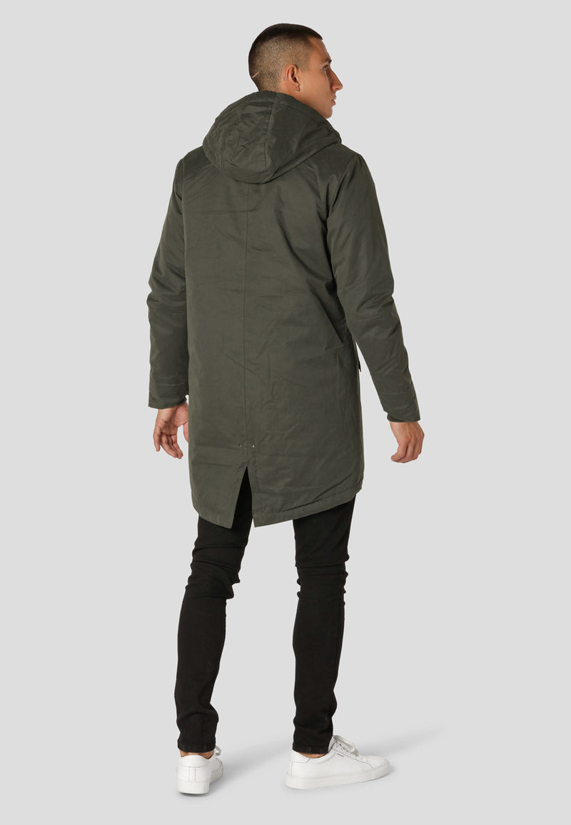 Man wearing a long green coat on a white background