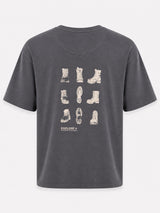 A dark gray short-sleeve t-shirt with a graphic print of various boot illustrations on the back, featuring the brand name 'EXPLORE+' and 'SANTA FE, NM' printed below.