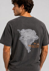 A man wearing a black washed t-shirt, viewed from the back. The shirt features a large distressed gray map graphic of South America with orange text reading 'THE ICE CAPES' and 'MEXICO' printed underneath.