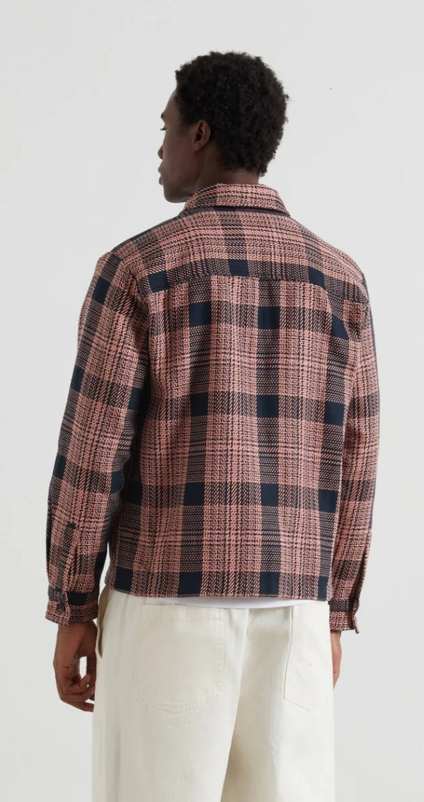 Person wearing a plaid overshirt and white pants on a white background