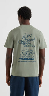 Person wearing a light green t-shirt with 'Lost & Found Objects Society' design on the back.