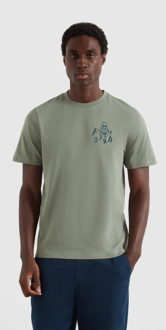 Person wearing a green t-shirt with a small graphic on a white background