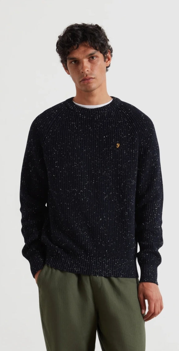 Man wearing a dark sweater with a small logo on a white background