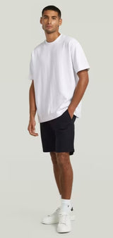 Man wearing a white t-shirt and navy shorts on a light gray background