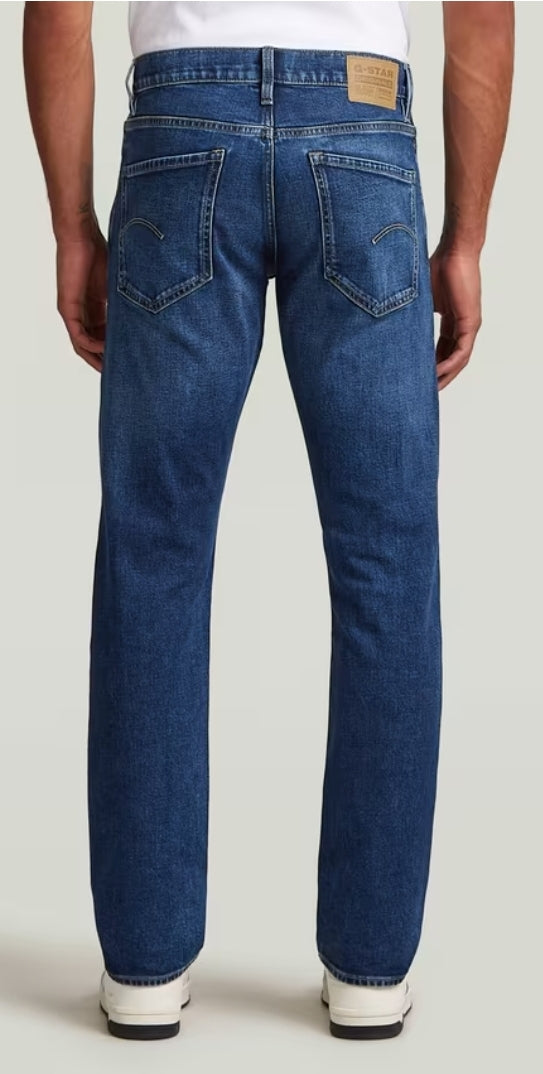 Blue jeans worn by a person on a plain background
