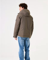 Person wearing a green jacket and blue jeans on a white background