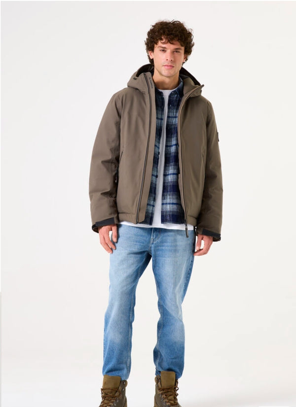 Man wearing a green jacket, plaid shirt, and blue jeans on a white background