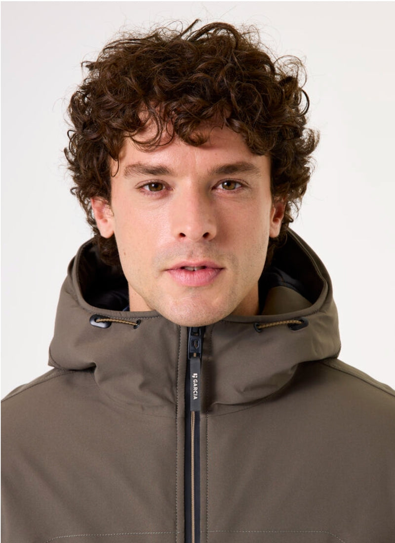 Man wearing a green hooded jacket against a white background