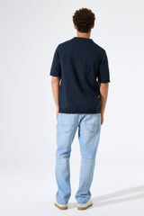 Person wearing a navy polo shirt and light blue jeans on a white background