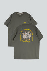 An olive green t-shirt shown from both the front and back against a light gray background. The front features a small yellow anchor graphic on the chest, while the back displays a large graphic of four cartoon seagulls with yellow text reading 'EAT SHIT SCREAM REPEAT' and 'SEAGULLS SQUAD'.