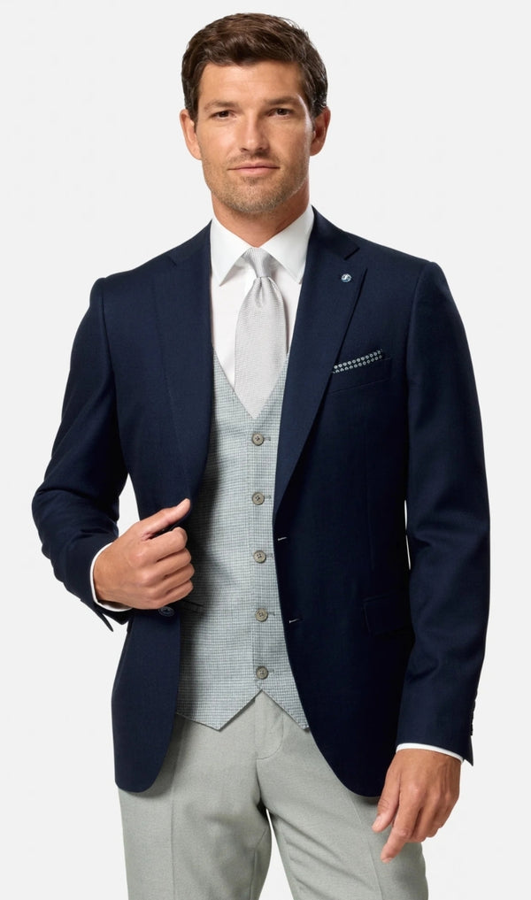 Man wearing a navy blazer, light green vest, and white shirt on a white background