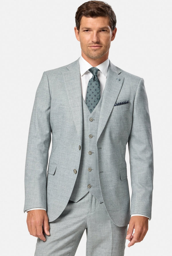 Man wearing a light green houndstooth suit with a white shirt and patterned tie on a white background